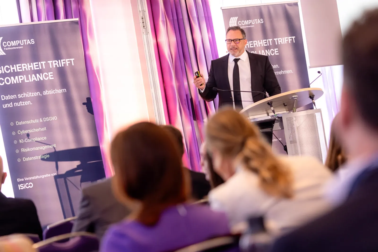 Referent am Rednerpult zwischen COMPUTAS Roll-ups